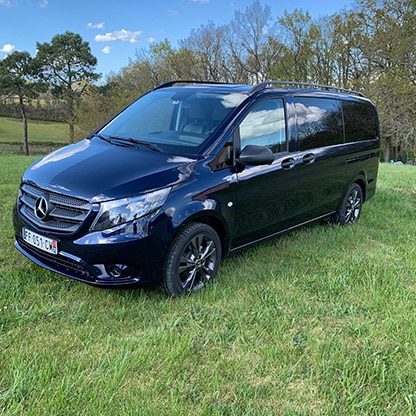 Van Mercedes Vito bleu foncé, plaque FF-051-CW, sur herbe verte. Ciel bleu et arbres en fond. Idéal transport VTC.